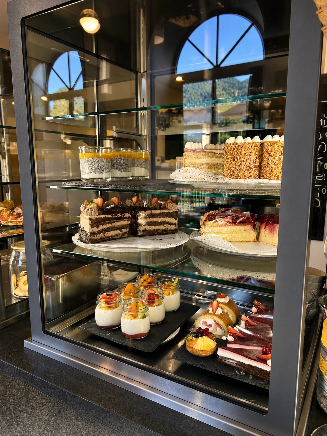 Tortenvitrine mit Kuchen und Dessertgläsern — Konditorei Café Rose Sterzing